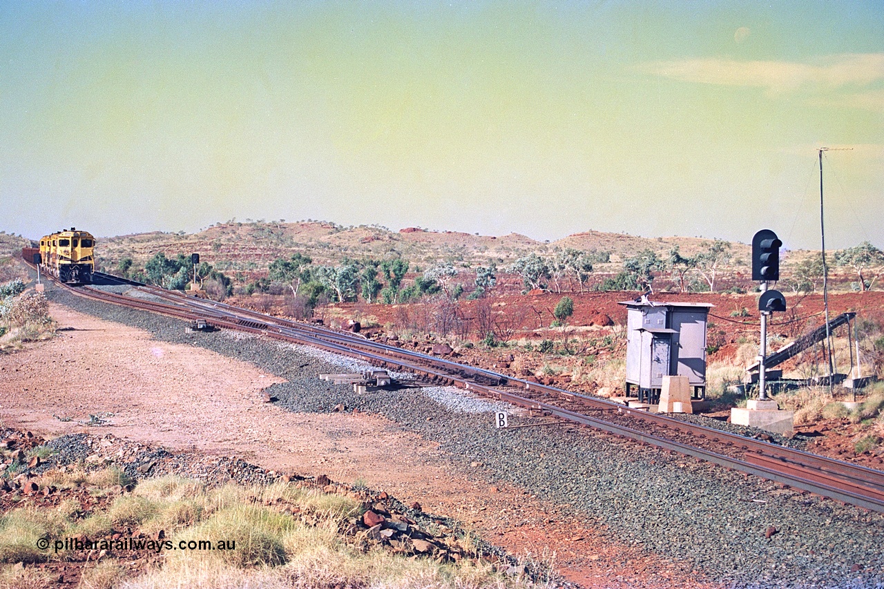 256-07
Maitland Siding located between the 92.8 and 95.1 km on the Cape Lambert line, view of the south end points and swing nose frog with dragging detector bars, solar panel and cabinets for signal and point control with an empty train sitting in the passing track awaiting a meet. May 2002.
