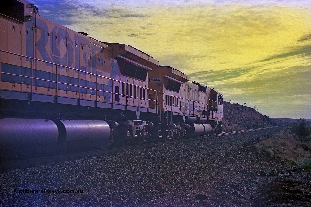 256-34
At the 89.6 km grade crossing the loaded train behind the quad CM40-8M working of 9414, 9420, 9410 and 9425 rolls across the crossing and heads down the 1.26 percent grade. 9414 was built by AE Goodwin NSW as an ALCo M636 model in December 1971 with serial number G-6060-5 and part of the original order for five units. Locomotive was delivered to Robe River in January 1972 with Bechtel Pacific road umber 262.005 for construction use and was renumbered 1714 when that was completed. 9414 was rebuilt by Goninan WA in November 1991 to become an CM40-8M model with serial number 8206-11 / 91-124. May 2002.
Keywords: 9414;Goninan;GE;CM40-8M;8206-11/91-124;rebuild;AE-Goodwin;ALCo;M636;G6060-5;