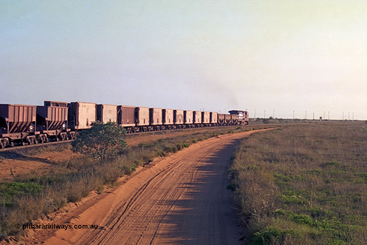 257-27
Goldsworthy Junction, an empty train runs between the junction and the Broome Rd crossing behind the standard single locomotive 5646 'White Springs', a Goninan 1992 built GE CM40-8 model with serial number 5244-11 / 92-135. The four styles of waggon in use are visible, behind the loco are three Golynx waggons, then a number of Gunderson USA builds, the ribbed type is a Portec USA built and then following are the Tomlinson WA and Scotts of Ipswich built 70 ton waggons. Late 2001.
