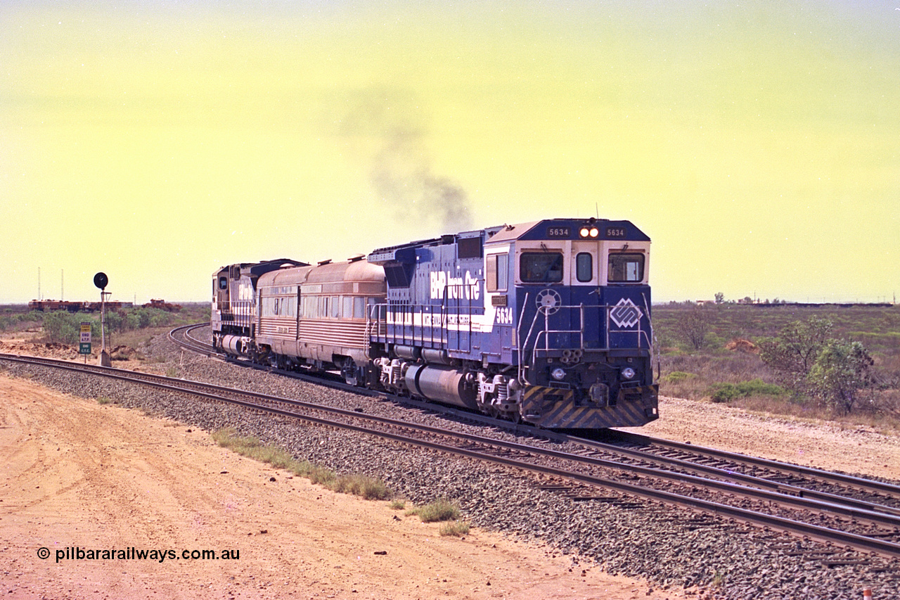 267-19
Goldsworthy Junction, CM40-8M GE unit 5634 'Boodarie' serial number 8151-07 / 91-120 leads the Sundowner Special on the Newman mainline leg of the Goldsworthy Junction and triangle, with the Sundowner coach in the middle and sister CM40-8M 5653 bringing up the rear.
This train, and the empty before it, were delayed due to a jamming switch for the transfer road where Tamper 2 and Ballast Regulator 31 are holding track.
 They can be seen behind the signal sitting on the transfer road.
 Friday 12th of April 2002.
Keywords: 5634;Goninan;GE;CM40-8M;8151-07/91-120;rebuild;AE-Goodwin;ALCo;C636;5457;G6027-1;