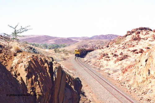 283-29
Near Woodbrook as the train rounds the curve just north of the 38.5 km grade crossing and through the cutting that will see it pass under the water pipe bridge behind the quad Robe River CM40-8M working of 9414, 9420, 9410 and 9525 with 202 waggons bound for Cape Lambert. May 22, 2002.
