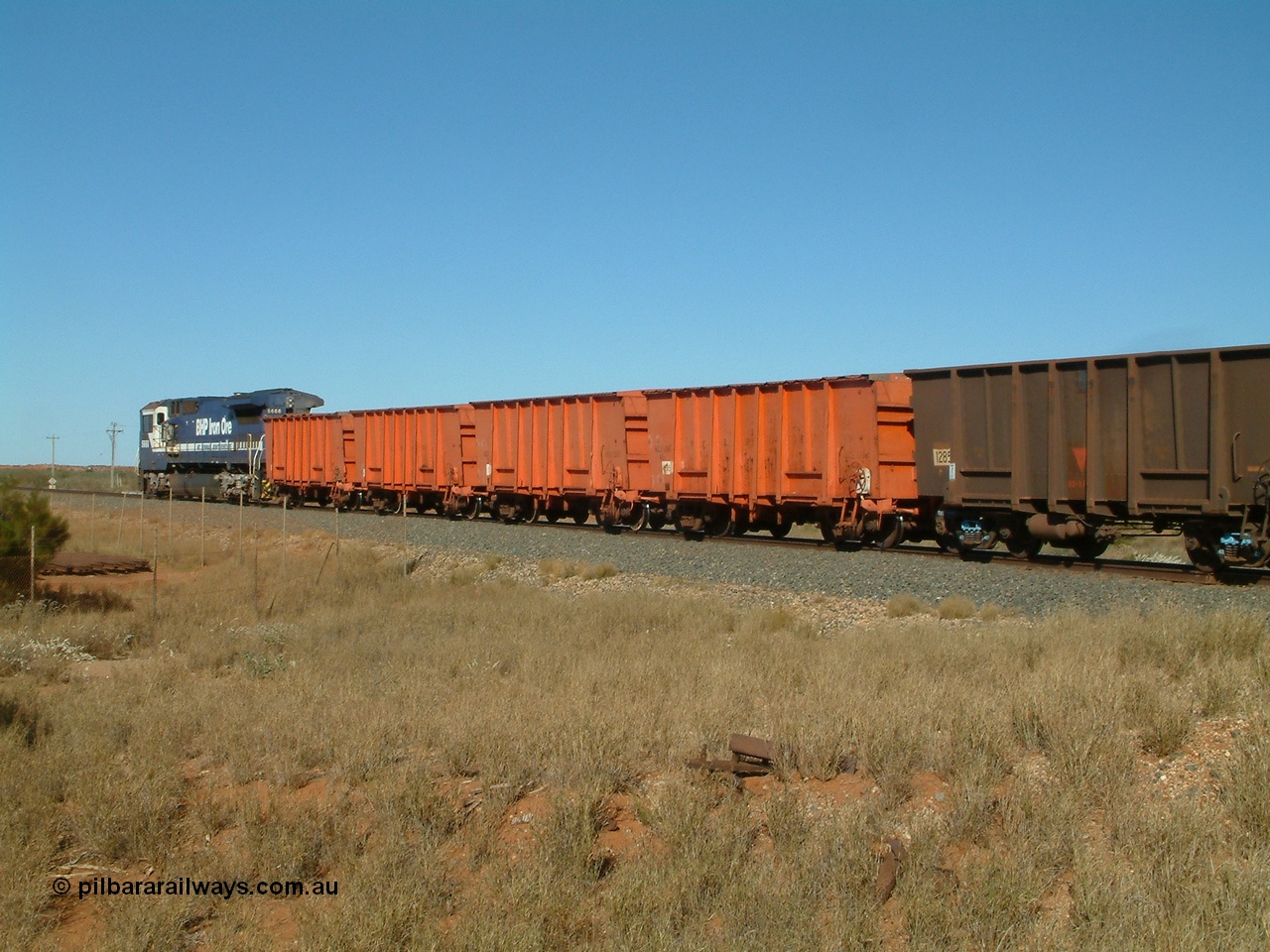 040806 091154
Goldsworthy Junction, trailing view of the weighbridge test train with the four orange weighbridge test waggons and two Comeng built ore waggons to provide braking, 5666 is the power.
