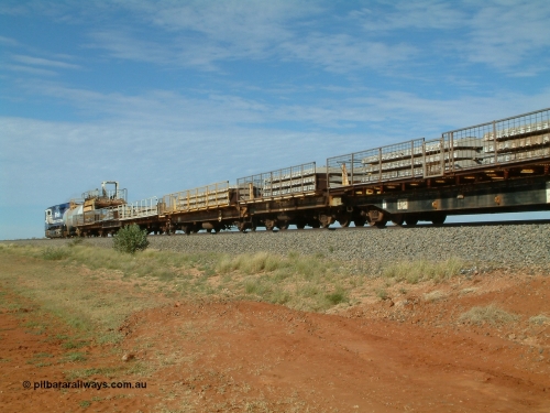 6701 Mt Newman Mining Workshops 040502 085554
Mooka Siding, trailing view of the 'Pony' heading south, 50 ton waggon 6701, one of three 'special' waggons converted from Magor USA built ore waggons, loaded with concrete sleepers is in the middle with former Goldsworthy flat waggon 8704 closet to camera. 
Keywords: Magor-USA;BHP-pony-waggon;