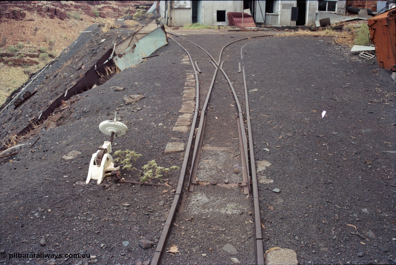 194-06
Wittenoom Gorge, Colonial Mine, asbestos mining remains, view looking south, set of points with cheese knob lever, the right track leads to the mine adit which can just be made out on the far right corner, the track on the left is the 'dump road' with the chute for the waggon discharge to gravity feed down to the crusher building.
