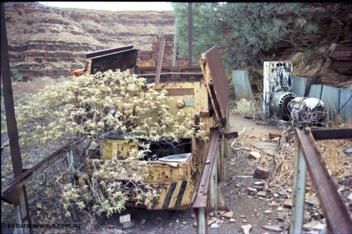 194-19
Wittenoom, Colonial Mine, asbestos mining remains, English Electric battery locomotive hauler and No.1 battery compartment open with batteries removed, workshops area, GEMCO Hauler behind it. Small MG DC generator set for battery charging behind at right, gorge in the background looking south.
