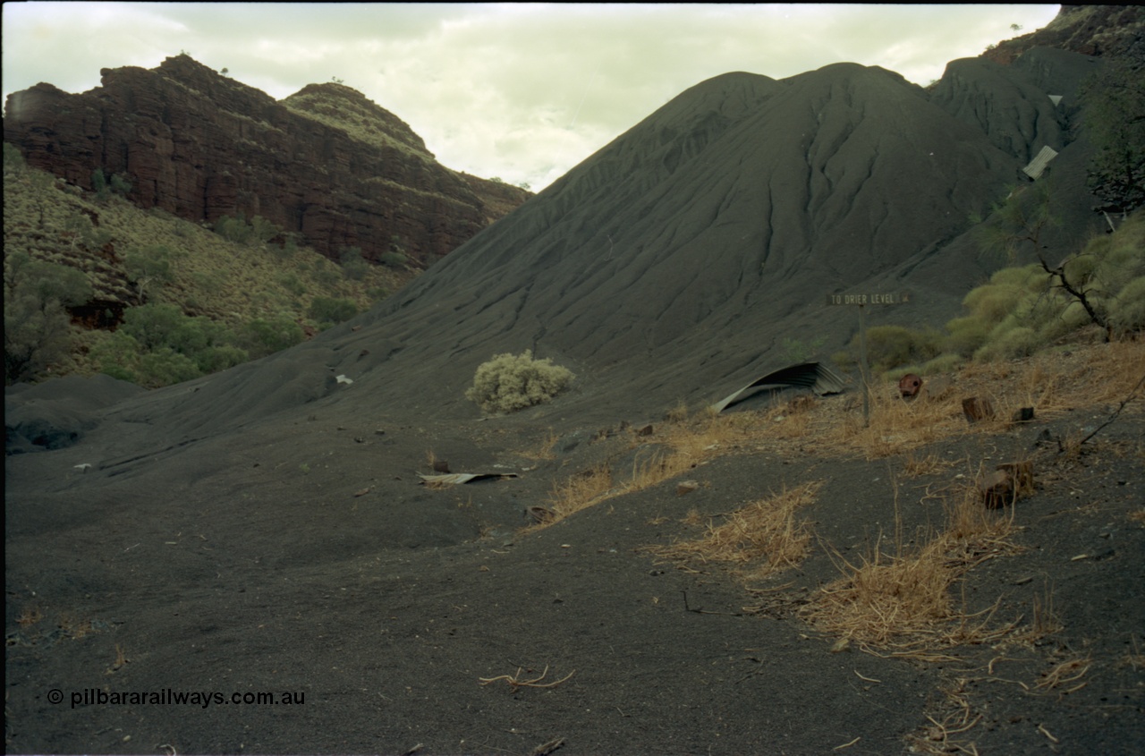 195-28
Wittenoom Gorge, Australian Blue Asbestos or ABA Colonial Mill, view of tailings which weather has eroded over the roads, direction sign to Drier Level still visible.
