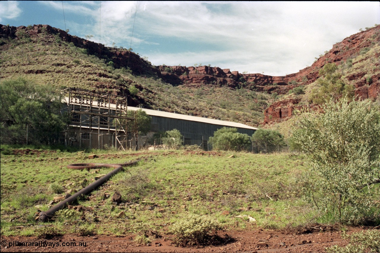 196-24
Wittenoom Gorge, view of power station generating hall with high voltage aerial conductors and the cooling water pipe visible.
