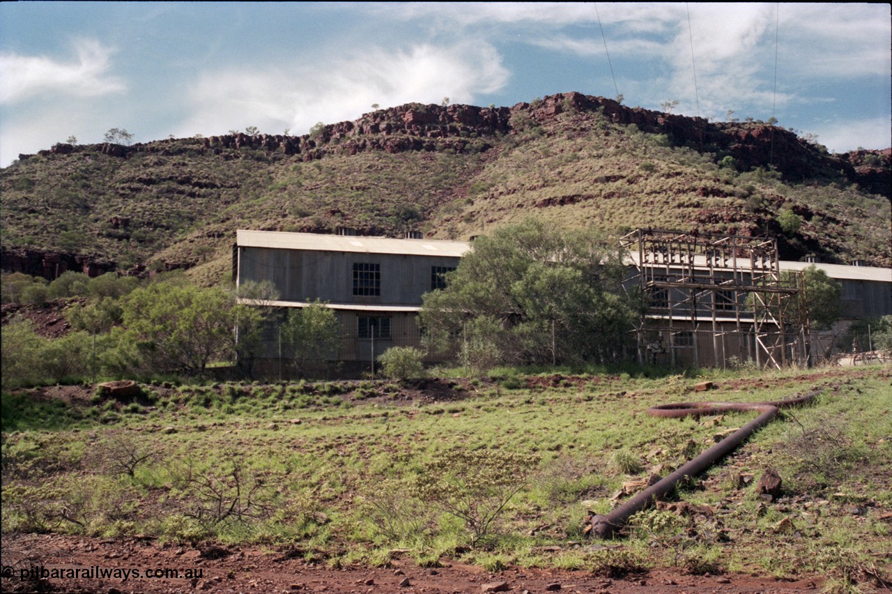 196-25
Wittenoom Gorge, view of power station generating hall with high voltage aerial conductors and the cooling water pipe visible.
