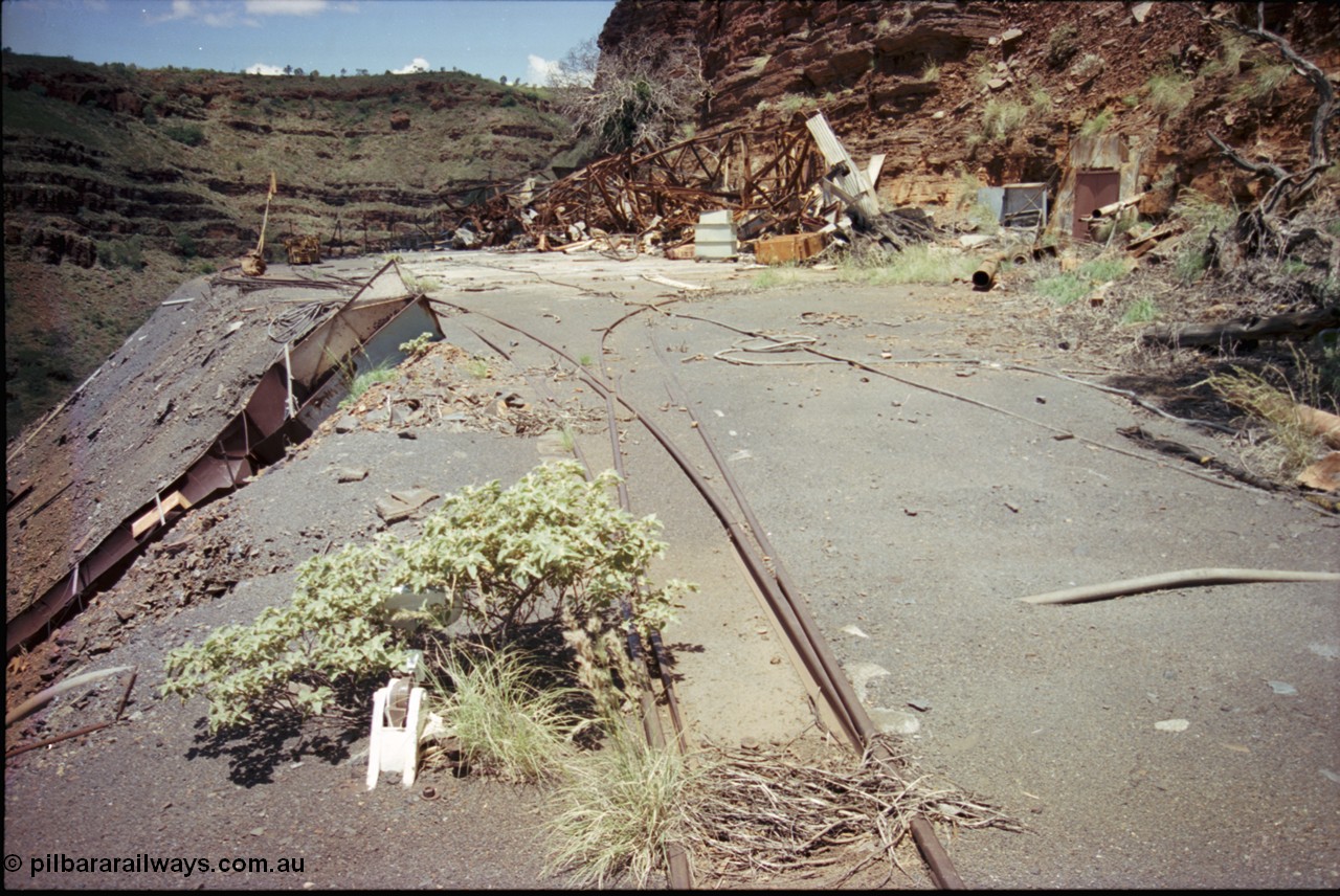 197-22
Wittenoom, Colonial Mine, asbestos mining remains, view of the points leading to the mine adit on the right, and past the discharge slide chute on the left. The loop road is visible in the distance, with the demolished underground offices and lamp room pushed up against the gorge wall. Mancha #4 in the distance.
