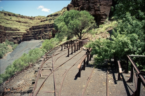 197-09
Wittenoom, Colonial Mine, asbestos mining remains, view looking south west of the open air locomotive storage roads with the battery off-take racks. The track used to continue around to the mine adits in the background.
