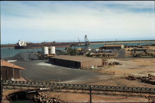 198-23
Port Hedland Port, view of the hard stand and overview of the PHPA, manganese is stockpiled around the former Cockburn Cement silos, new bulk loader under construction, tug pen visible along with single berth at BHP Finucane Island.
