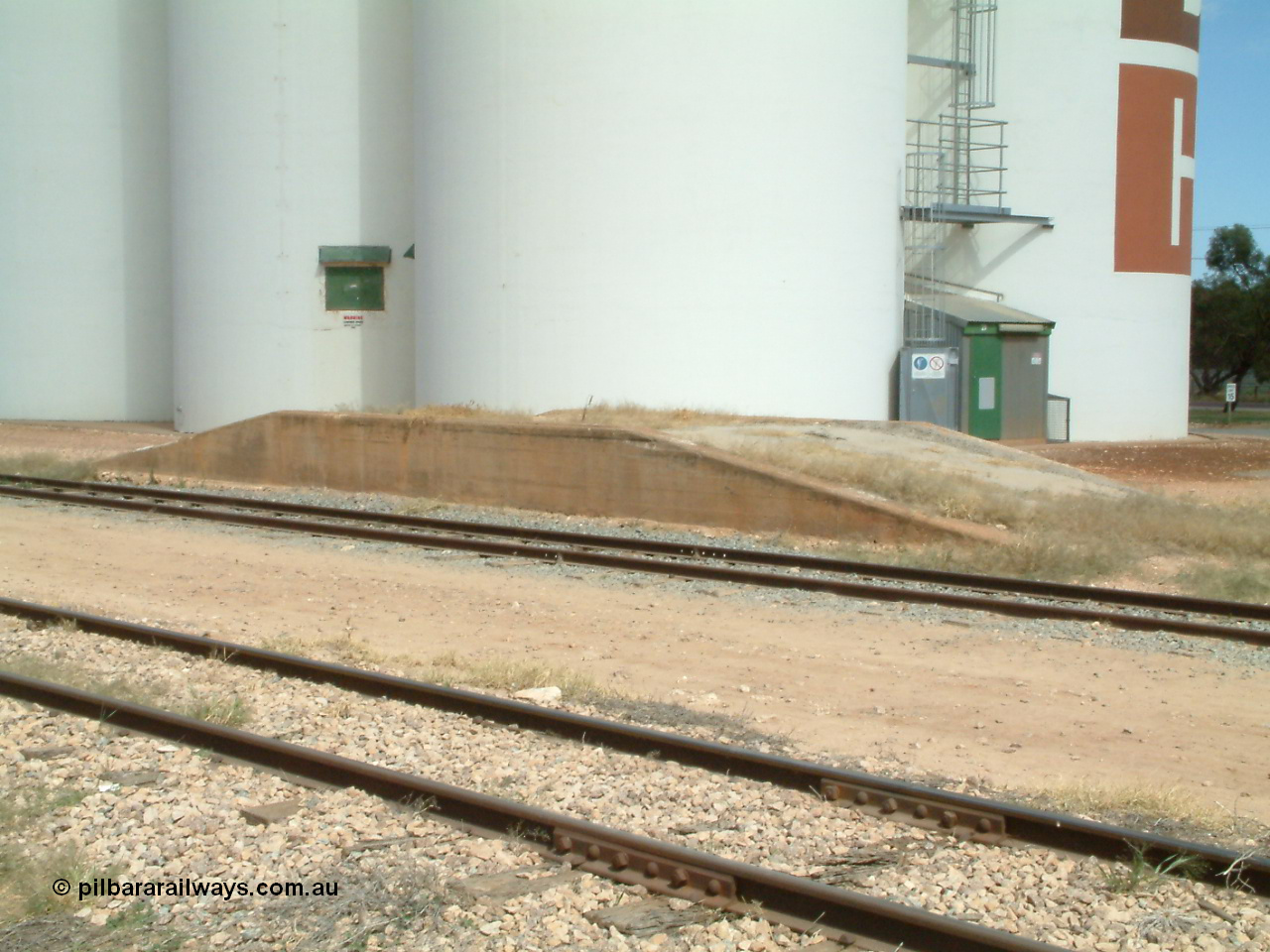 030405 133054
Wudinna, yard view across mainline and siding with loading ramp, SACBH silo complex behind, 5th April 2003.
