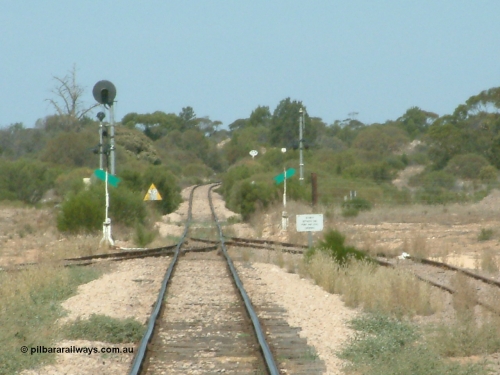 030405 140102
Kyancutta, yard view looking south along the narrow gauge mainline with the siding point levers and indicators with the Eyre Highway grade crossing and one of only three electrically lit signals on the Eyre Peninsula Division. The cast iron 'Yard Limit' sign can be made out in the distance, April 5, 2003.
