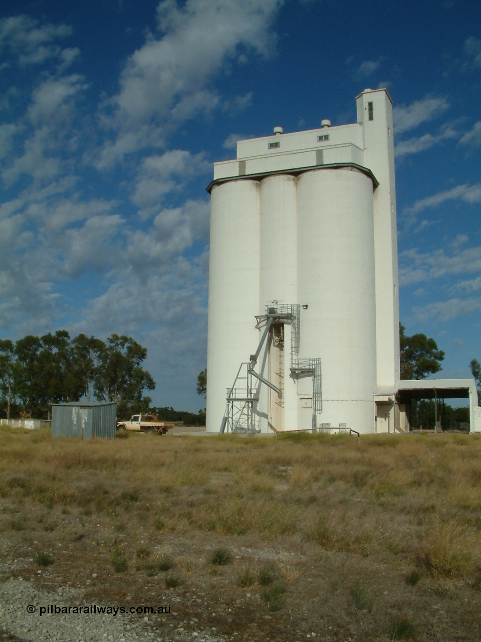 030406 084350
Tooligie, elevation view of the concrete style silo complex and outflow spout, Block 1, station train control cabin and loading ramp visible on the left. 6th April 2003.
