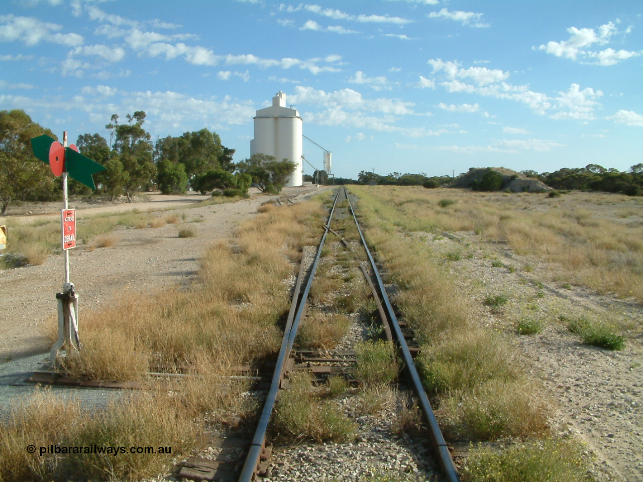 030406 084715
Tooligie, station yard overview looking north from the south end points, point lever and indicator, silo complex and outflow spouts on the left, old ballast pile on the right, former siding to the right of the mainline can still be made out for ballast loading site, 6th April 2003.
