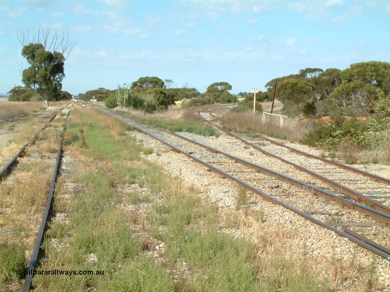 030406 092756
Yeelanna, yard view looking south, shows mainline and grain siding running south and branch line to Kapinnie and former Mount Hope branch curving away to the right across a culvert and past a cast Yard Limit sign. 6th April 2003.
