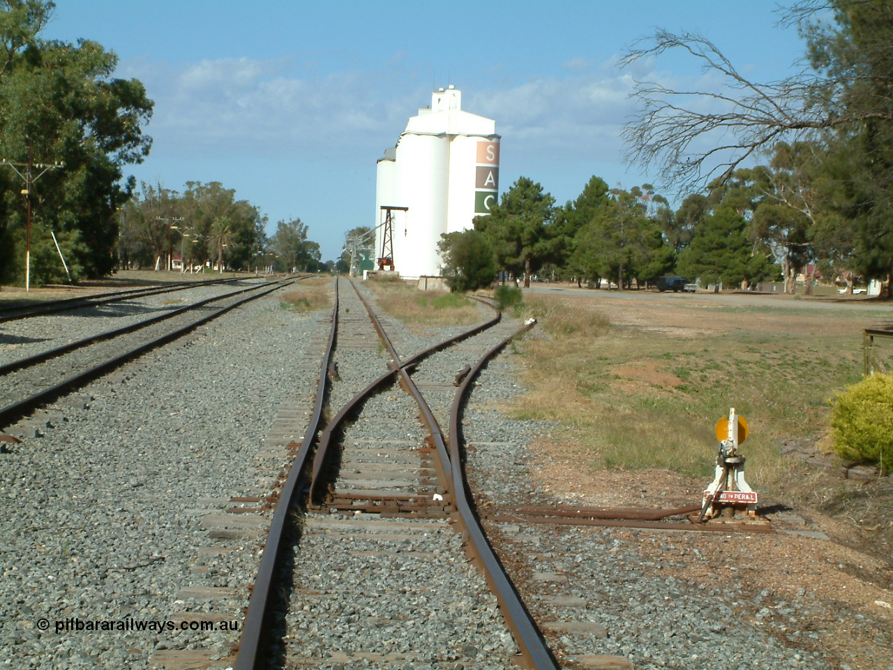 030406 094331
Cummins, yard view looking south along the grain siding with the points, lever and indicator for the goods loading ramp siding, formation of former triangle can be seen as the mound curving away to the right. 6th April 2003.
