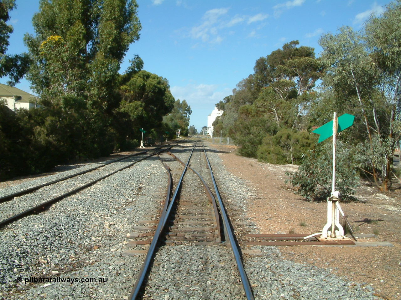 030406 094714
Cummins, yard overview looking south down the mainline from Thevenard with the line from Buckleboo coming in on the left, points, levers and indicators for the crossovers being visible with crib crossing and concrete silos in the distance. 6th April 2003.
