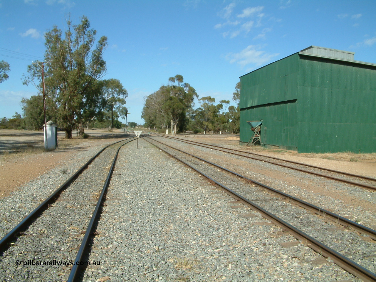 030406 095704
Cummins, yard view looking south, Buckleboo line - siding converging with mainline in the middle with grain siding on the right. Train control concrete booth on the left, Railway Tce grade crossing, green possible former fertiliser shed. 6th April 2003.
