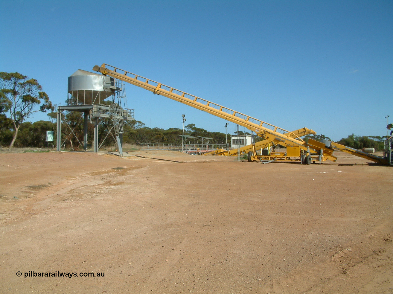 030406 100824
Cummins, expanded view of the grain bunker rail unloading facility with dual DOH 'Drive Over Hopper' and stackers for loading road vehicles and with the overhead outflow bin and feed conveyors for loading rail waggons. 6th April 2003.
