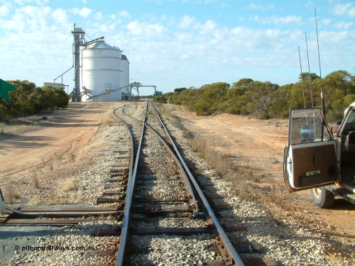 030406 082324
Murdinga, yard overview looking south down the mainline from the north end, with grain siding and silo complex with outflow spout on gantry over both tracks. April 6, 2003.

