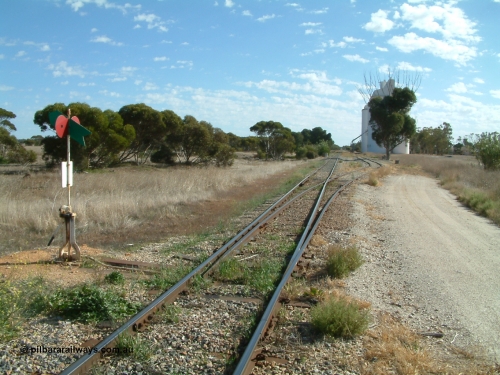 030406 093000
Yeelanna, station located at the 81.7 km, original terminus of line in April 1909, then junction for line to Mount Hope in October 1914. Station yard overview from the south end looking north, points, lever and indicator for the grain siding with concrete silo complexes in the background. The branch line to Kapinnie and former Mount Hope is just visible through the trees on the raised embankment. April 6, 2003.
