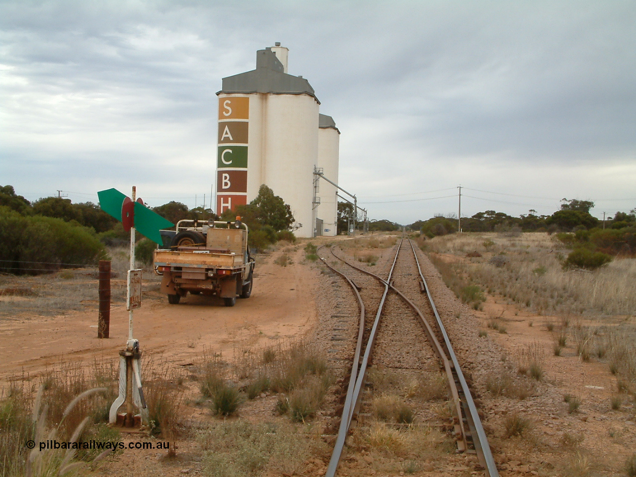 030407 085559
Yaninee, station yard overview looking north for the south end, concrete SACBH silo complexes, points, lever and indicator, mainline can be seen running straight into the distance. 7th April, 2003.
