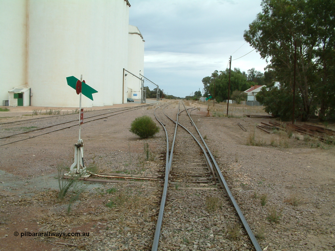 030407 094128
Minnipa, station yard overview looking north from the south end of yard down mainline, concrete silo complexes and out-flow spouts on the left with sidings running behind camera. Train control booth and shelter can be made out behind the second point lever - indicator. 7th April , 2003.
