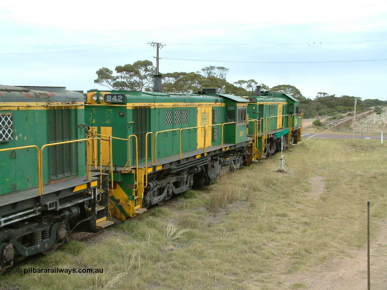 030407 100500
Minnipa, north bound empty grain train shunts across the grade crossing for Minnipa - Yardea Rd behind a trio of former Australian National Co-Co locomotives with rebuilt former AE Goodwin ALCo model DL531 830 class ex 839, serial no. 83730, rebuilt by Port Augusta Workshops to DA class, leading two AE Goodwin ALCo model DL531 830 class units 842, serial no. 84140 and 851 to shunt off empty waggons into the grain siding. 7th April, 2003.
Keywords: 830-class;842;AE-Goodwin;ALCo;DL531;84140;