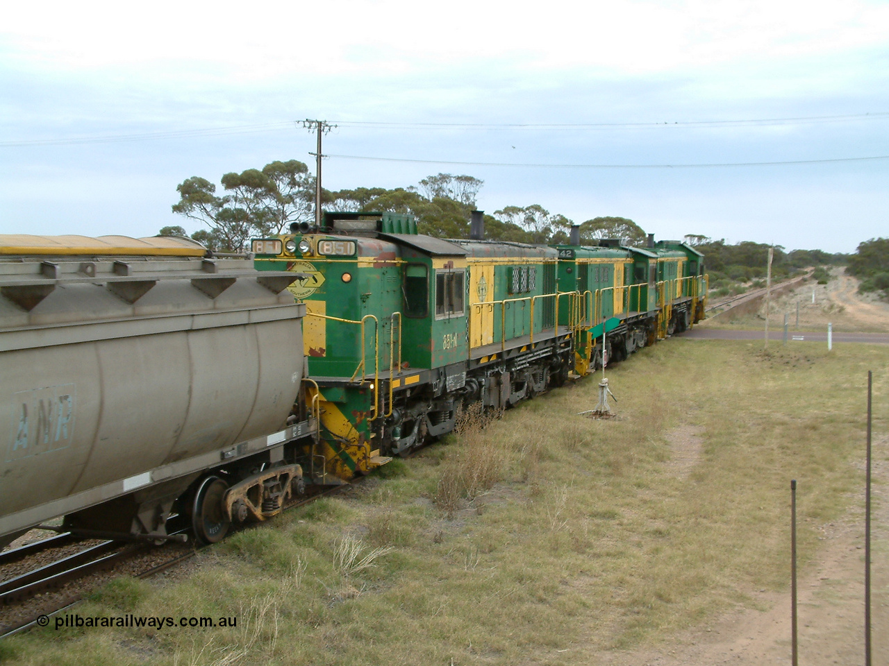 030407 100506
Minnipa, north bound empty grain train shunts across the grade crossing for Minnipa - Yardea Rd behind a trio of former Australian National Co-Co locomotives with rebuilt former AE Goodwin ALCo model DL531 830 class ex 839, serial no. 83730, rebuilt by Port Augusta Workshops to DA class, leading two AE Goodwin ALCo model DL531 830 class units 842, serial no. 84140 and 851 serial no. 84137, 851 having been on the Eyre Peninsula since delivered in 1962, to shunt off empty waggons into the grain siding. 7th April, 2003.
Keywords: 830-class;851;AE-Goodwin;ALCo;DL531;84137;