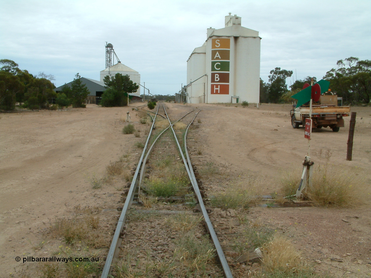 030407 104644
Poochera, station yard overview looking north from south end of yard, point levers and indicators for sidings, on the left is the horizontal grain shed with an Ascom style silo complex behind it, on the right the goods shed can be made out along with the SACBH concrete silo complexes. 7th April 2003.
