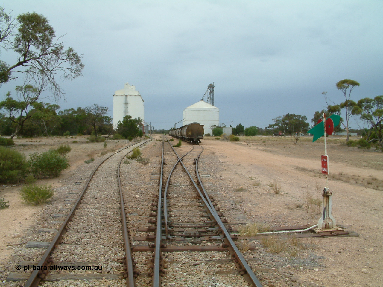 030407 105354
Poochera, yard overview looking south from the north end grain siding points, crane and goods shed just visible on the left of the goods siding, loaded grain rake on the grain siding with the Ascom silo complex to the right of the waggons. 7th April 2003.
