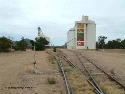 030407 104705
Poochera, station yard overview looking north from south end of Goods Siding 2, point lever and indicator for siding, on the left is the horizontal grain shed with an Ascom style silo complex behind it, on the right the goods shed can be made out along with the SACBH concrete silo complexes. April 7, 2003.
