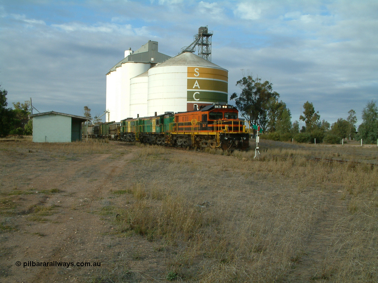 030409 080101
Warramboo, empty grain train arrives just after 0800 and stops for a crew change. Rebuild unit DA 7 in Australian Southern orange and black livery leads a pair of AE Goodwin built ALCo model DL531 830 class units 872 and 871 framed between the station building and the SACBH concrete silo complex.
Keywords: DA-class;DA7;83713;Port-Augusta-WS;ALCo;DL531G/1;48-class;4813;rebuild;