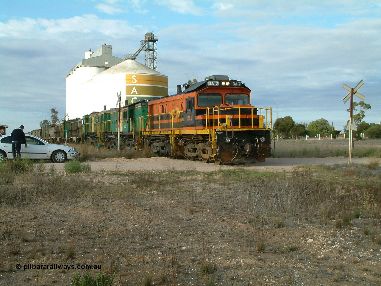 030409 080651
Warramboo, empty grain prepares to get underway following a crew change. Rebuild unit DA 7 in Australian Southern orange and black livery leads a pair of AE Goodwin built ALCo model DL531 830 class units 872 and 871, the relieved crew get in their car with the SACBH concrete silo complex behind.
Keywords: DA-class;DA7;83713;Port-Augusta-WS;ALCo;DL531G/1;48-class;4813;rebuild;