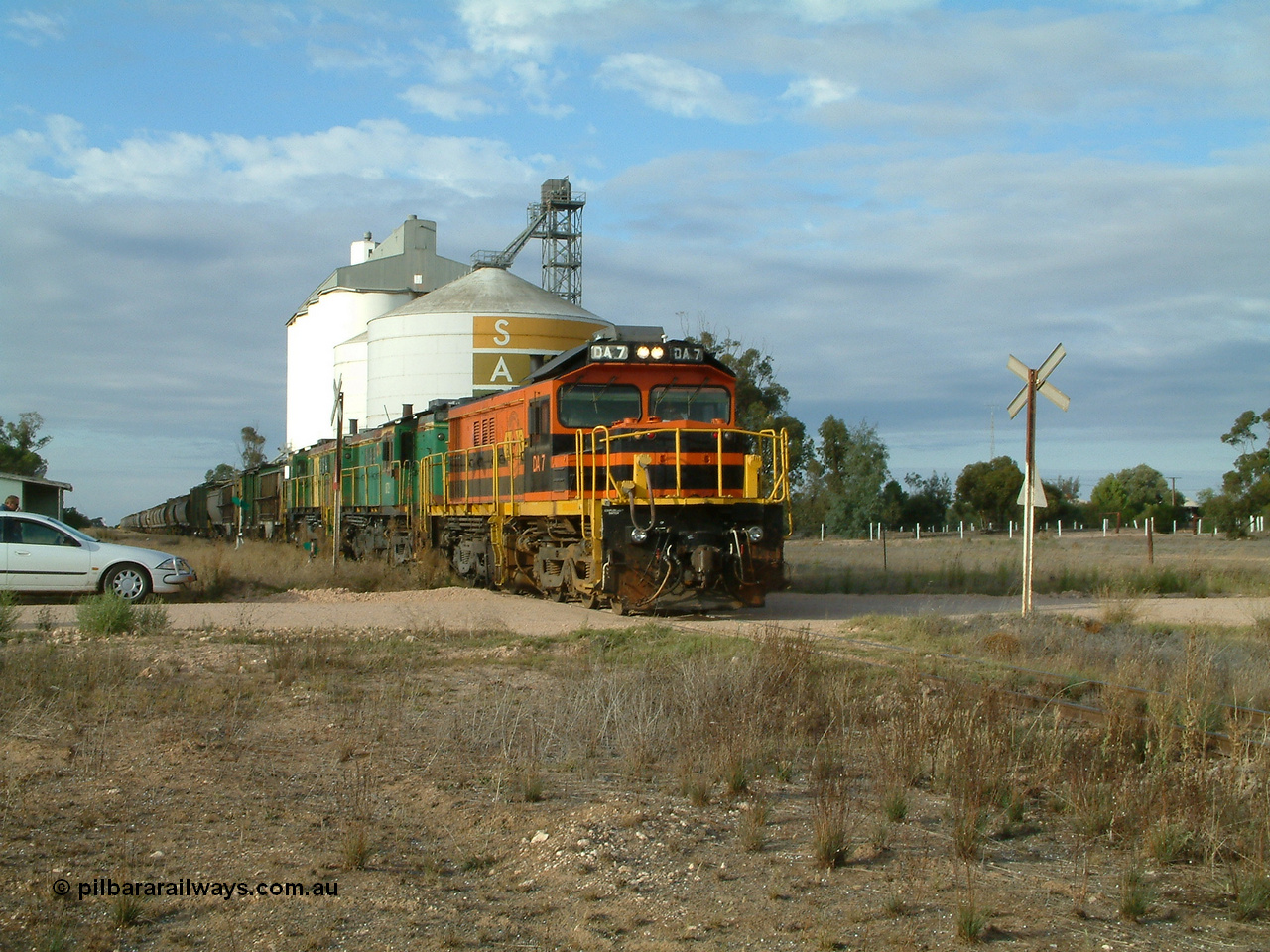 030409 080705
Warramboo, empty grain prepares to get underway following a crew change. Rebuild unit DA 7 in Australian Southern orange and black livery leads a pair of AE Goodwin built ALCo model DL531 830 class units 872 and 871, the long disused station building at left and the SACBH concrete silo complex behind.
Keywords: DA-class;DA7;83713;Port-Augusta-WS;ALCo;DL531G/1;48-class;4813;rebuild;