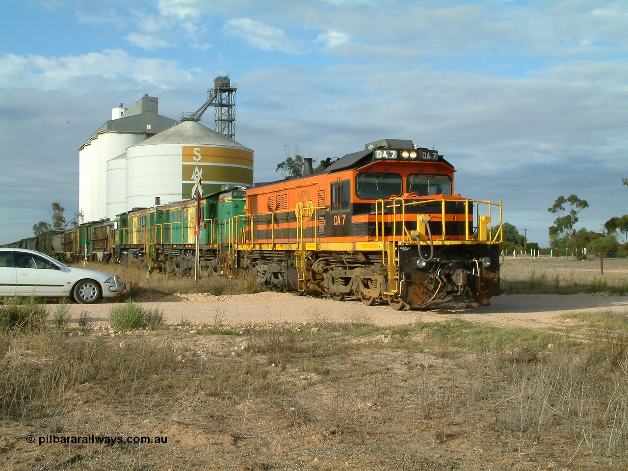 030409 080717
Warramboo, empty grain prepares to get underway following a crew change. Rebuild unit DA 7 in Australian Southern orange and black livery leads a pair of AE Goodwin built ALCo model DL531 830 class units 872 and 871, the relieved crew get in their car with the SACBH concrete silo complex behind.
Keywords: DA-class;DA7;83713;Port-Augusta-WS;ALCo;DL531G/1;48-class;4813;rebuild;