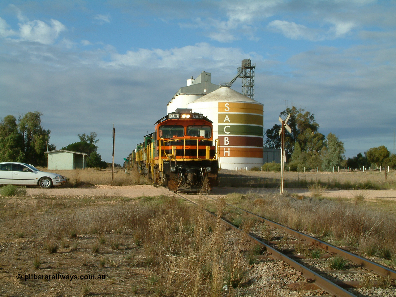 030409 080811
Warramboo, empty grain prepares to get underway following a crew change. Rebuild unit DA 7 in Australian Southern orange and black livery leads a pair of AE Goodwin built ALCo model DL531 830 class units 872 and 871, the relieved crew in the car with the long disused station building on the left and the SACBH concrete silo complex on the right rounding out the scene.
Keywords: DA-class;DA7;83713;Port-Augusta-WS;ALCo;DL531G/1;48-class;4813;rebuild;