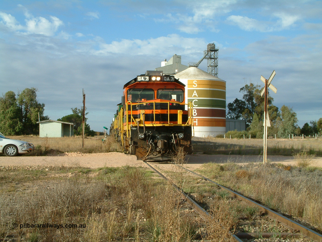 030409 080822
Warramboo, empty grain prepares to get underway following a crew change. Rebuild unit DA 7 in Australian Southern orange and black livery leads a pair of AE Goodwin built ALCo model DL531 830 class units 872 and 871, the relieved crew in the car with the long disused station building on the left and the SACBH concrete silo complex on the right rounding out the scene.
Keywords: DA-class;DA7;83713;Port-Augusta-WS;ALCo;DL531G/1;48-class;4813;rebuild;