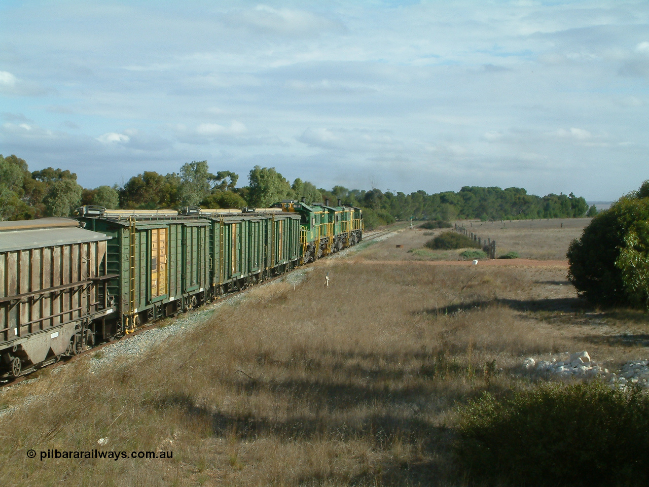 030409 152437
Ungarra, the peace is shattered as a loaded grain train storms upgrade through the station behind 830 class unit 851 AE Goodwin ALCo model DL531 serial 84137, fellow 830 class 842 serial 84140 and a rebuilt DA class unit DA 4 trailing view with the ENHV waggons as the continue south.
Keywords: ENHV-type;Societe-Gregg-de-Europ;NVD-type;ENBA-type;