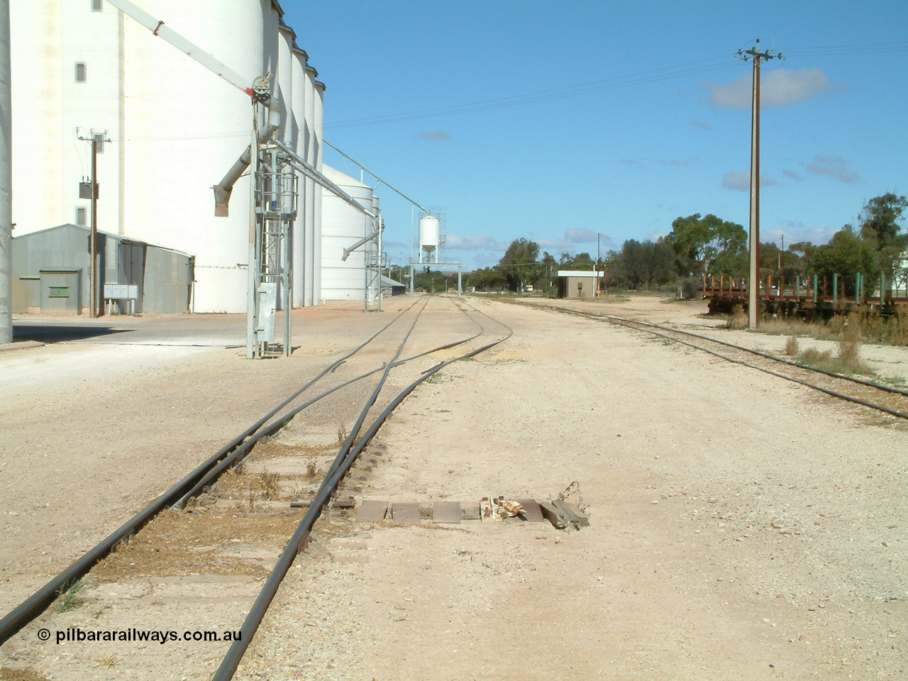 030411 110106
Kimba, station yard view looking south, point level is covered to allow road vehicles to travel over it as a tractor is sometimes used for shunting. The loadout spouts are evident along with the Ascom loadout silo and horizontal bunker beyond that.
