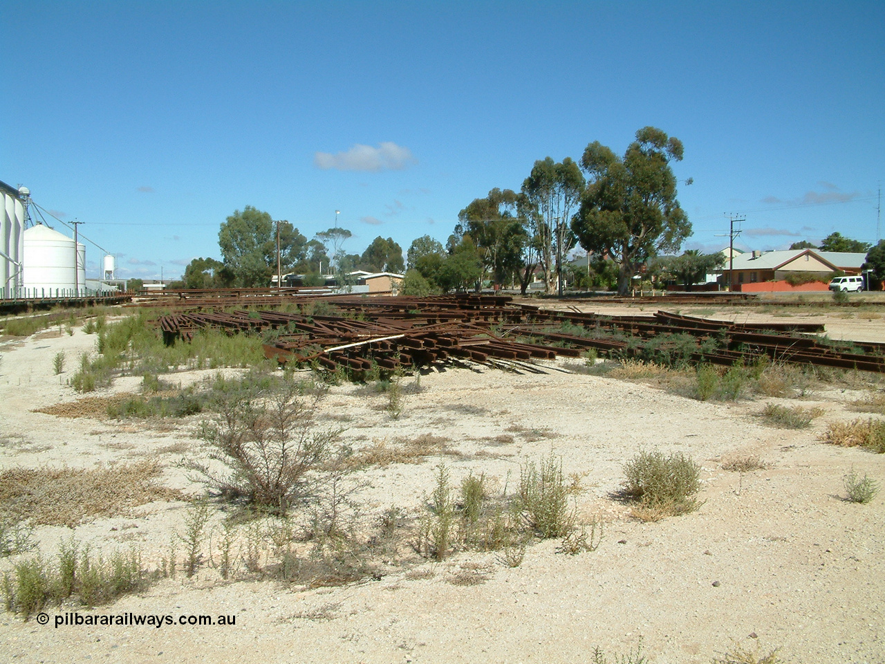 030411 110259
Kimba, view looking south with rail stockpile, silos and loadout bin with rail transport train on the left, station building can be just made out, crew barracks middle of frame in the distance.
