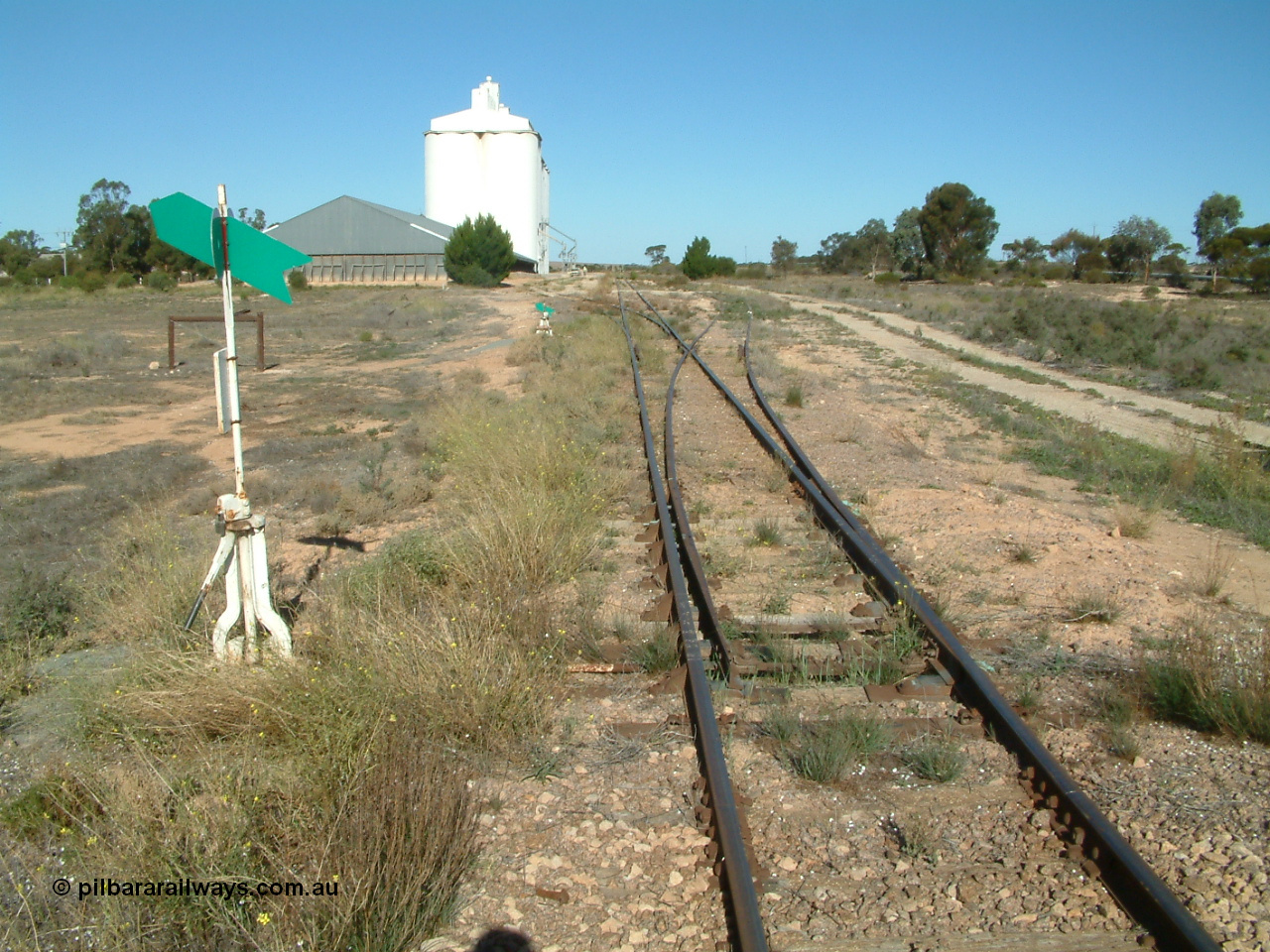 030411 154018
Wirrulla 333.2 km, yard overview looking south from the Thevenard end on Gawler Ranges Road, horizontal bunker with two blocks of concrete silos on the left.
