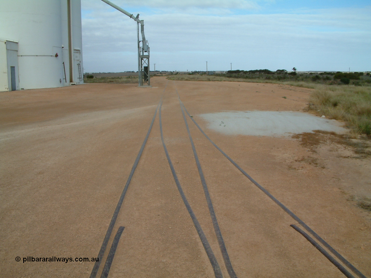 030414 154120
Penong, yard view looking east along the grain loop with concrete silo block 2 on the left and the crossover from the main to the loop coming in from the right. Station shelter is in the distance on the right.
