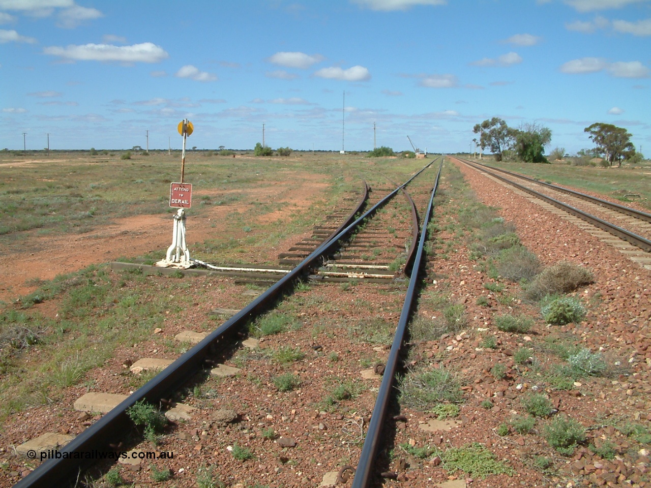 030415 140420
Kingoonya, located at the 426.5 km on the Trans Australian Railway, looking east along the loop siding with the mainline on the right and points and sidings off to the left, loading ramp and crane in distance, town located to the right. [url=https://goo.gl/maps/rY8C9mU9iF4tBmjF7]GeoData location[/url].
