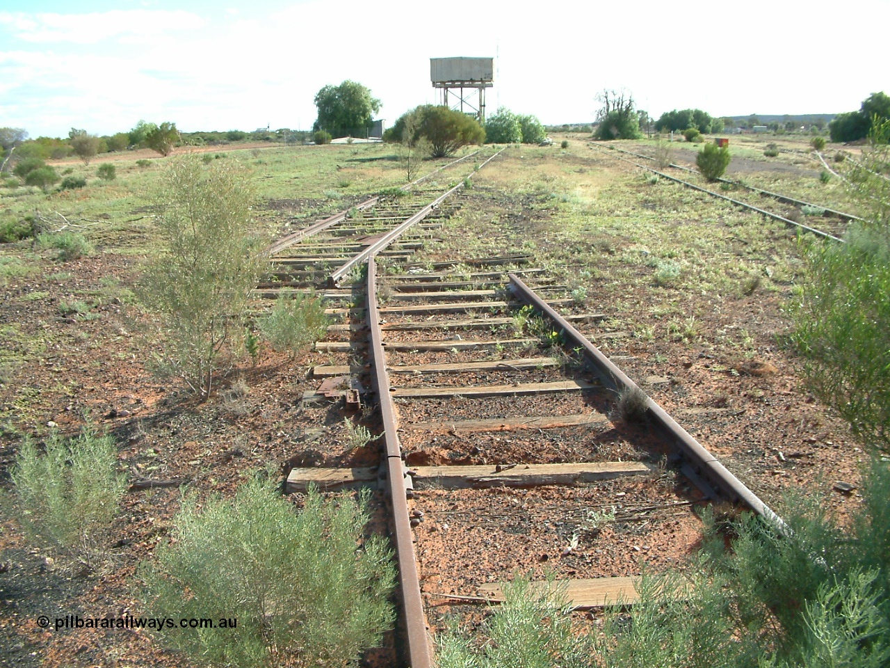 030415 155213
Tarcoola, at the 504.5 km, looking west, end of No. 1 Water Road running straight, removed points, No. 2 Loco, then No. 1 Loco and the points for the Camp Train Roads just visible on the right. Tank on stand and underground covered tank can be made out. [url=https://goo.gl/maps/y17pUsTYVeRwPsa67]GeoData location[/url]. 15th April 2003.
