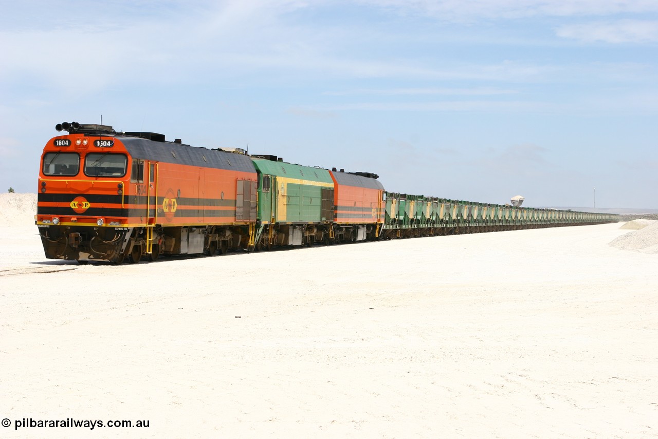 060113 2551
Kevin, standing on the mainline to Thevenard, and the train now identified as 6DD4 has commenced loading of gypsum but the 988 Cat front end loaders which takes about one and half hours to load. As the train reversed on the triangle the consist is the same heading back loaded with 1604 leading NJ 3 and 1601. 13th January 2006.
