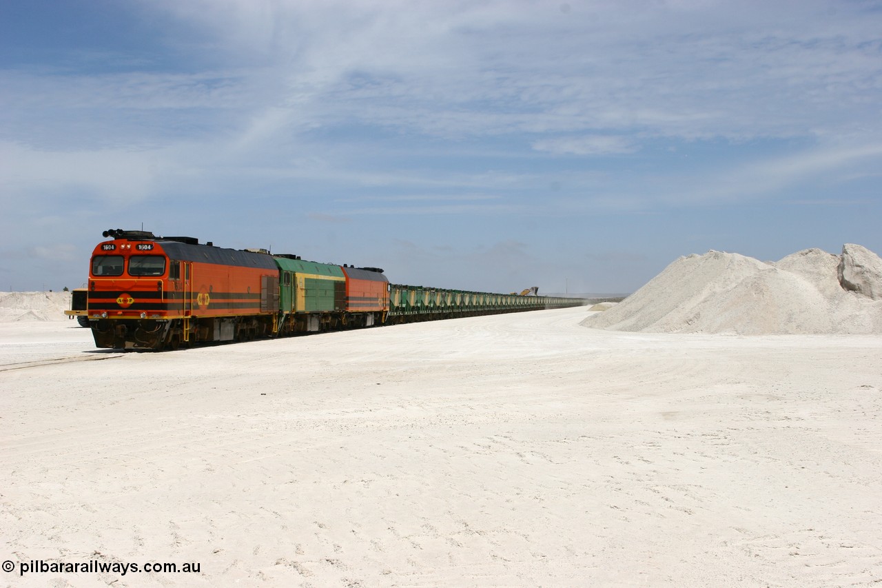 060113 2553
Kevin, standing on the mainline to Thevenard, and the train now identified as 6DD4 has commenced loading of gypsum but the 988 Cat front end loaders which takes about one and half hours to load. As the train reversed on the triangle the consist is the same heading back loaded with 1604 leading NJ 3 and 1601. 13th January 2006.
