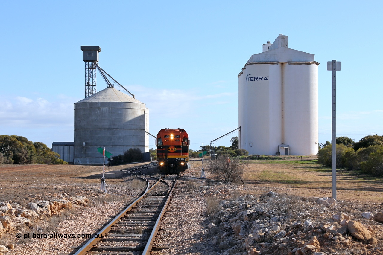 130704 0440
Kyancutta, located at the 203.1 km and opened in March 1916, overview of yard with Ascom silo complex on the left with new siding which was installed in 1970 and the eight cell concrete SACBH silo complex on the right as the second driver returns to the locomotive to depart south bound for Port Lincoln. 4th July 2013.
Keywords: 1200-class;1204;Clyde-Engineering-Granville-NSW;EMD;G12C;65-428;A-class;A1514;