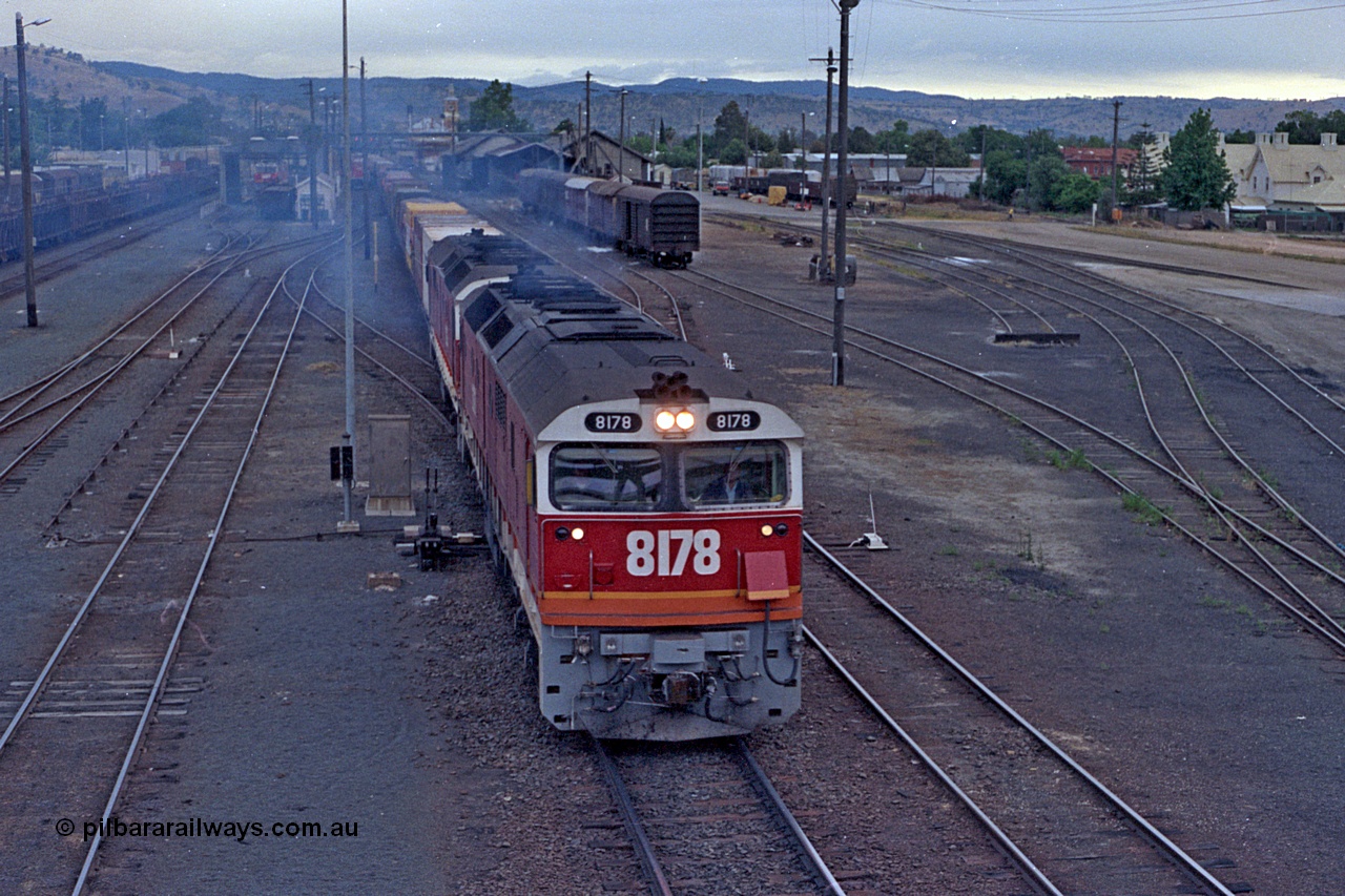 100-03
Albury station yard overview looking south, from Wilson Street footbridge, NSWSRA standard gauge 81 class 8178 Clyde Engineering EMD model JT26C-2SS serial 85-1097 double heading with a sister 81 class, both in candy livery, Sydney bound goods, 2 lever ground frame beside loco. [url=https://goo.gl/maps/nngpTA37VQekQpCt7]Geodata[/url].
Keywords: 81-class;8178;Clyde-Engineering-Kelso-NSW;EMD;JT26C-2SS;85-1097;